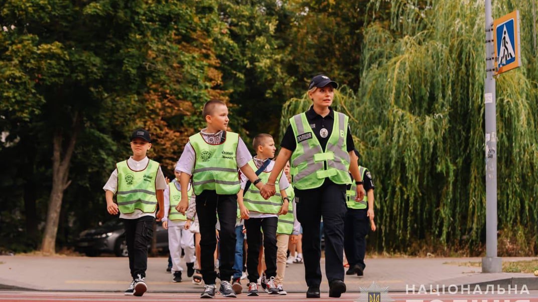 Офіцерка Служби освітньої безпеки переводить дітей через пішохідний перехід