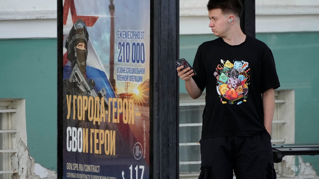 россиянин стоит возле билборда с рекламой рекрутинговой кампании в Санкт-Петербурге, сентябрь 2024 года