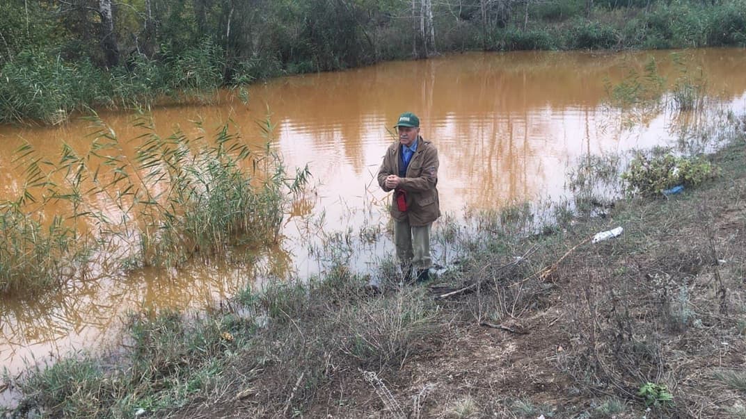Гидрогеолог Евгений Яковлев возле отстойника шахты с характерно оранжевой водой, Луганская область