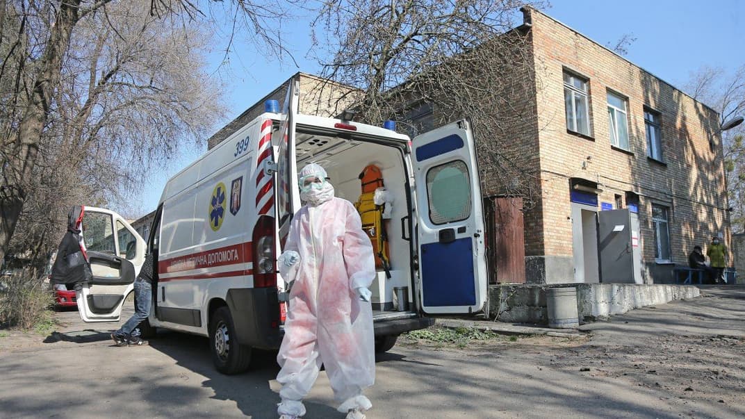 Медработник в защитном костюме возле автомобиля скорой помощи на территории Киевской городской клинической больницы №4, Киев, 3 апреля 2020 года