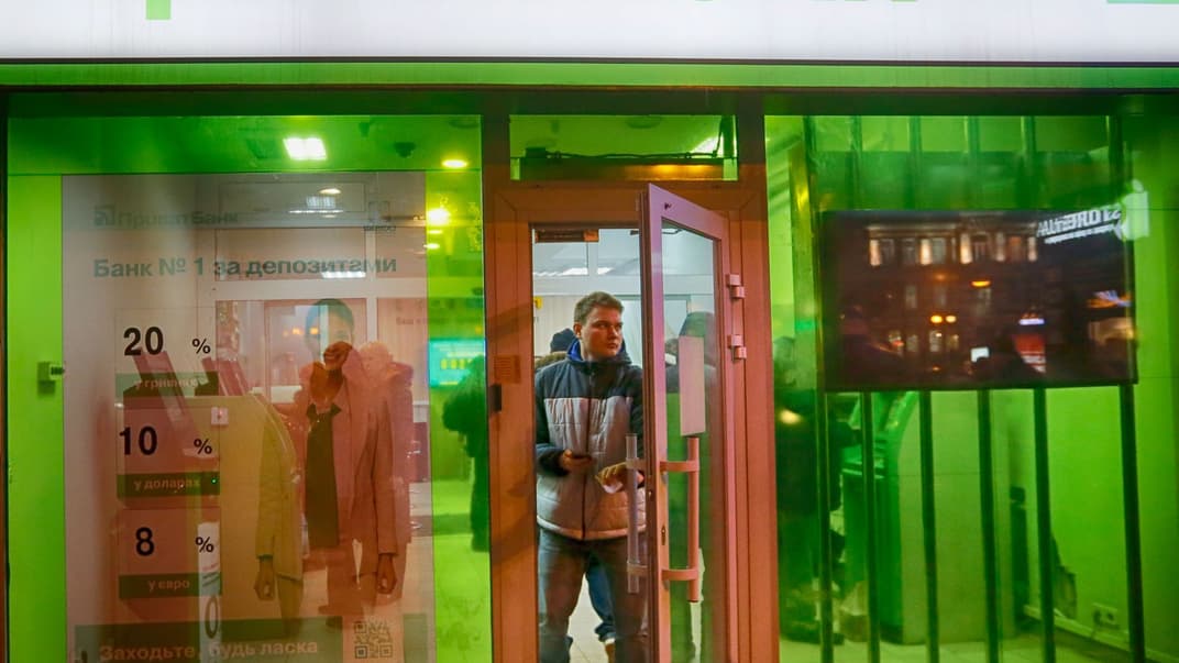 Клієнт виходить з офісу «ПриватБанку», коли інші клієнти беруть гроші з банкоматів установи в центрі Києва, Україна, 19 грудня 2016 року