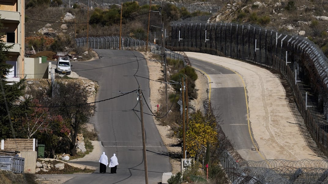 Жінки йдуть уздовж паркану біля так званої лінії Альфа, яка відокремлює контрольовані Ізраїлем Голанські висоти від Сирії, у місті Мадждаль-Шамс, 15 грудня 2024 року
