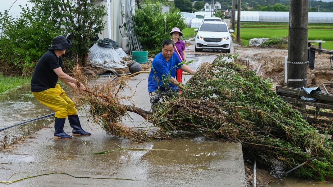 Місцеві жителі прибирають гілки та уламки, знесені повінню в Гансан-Мьон, провінція Південний Чхунчхон, Південна Корея, 17 липня 2025 року