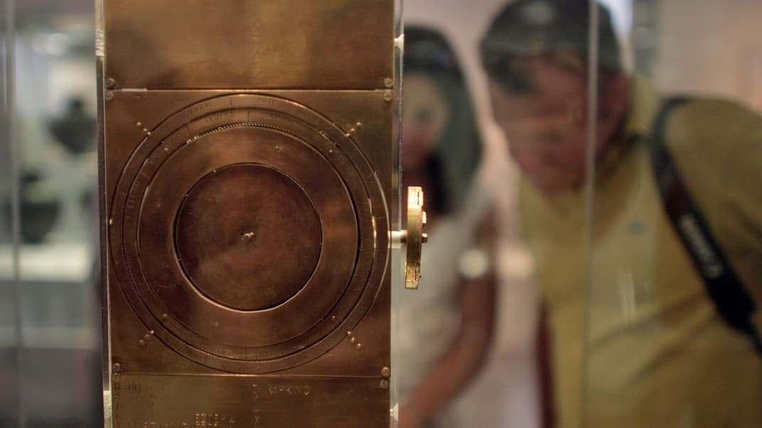 Посетители рассматривают модель древнего астрономического вычислительного устройства, известного как Антикитерский механизм, в Национальном археологическом музее Афин, 30 июля 2008 года