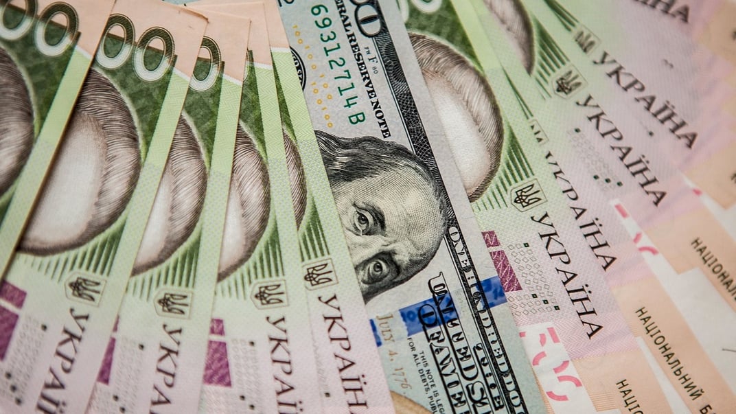 Иллюстративная фотография. 100 долларов среди 500-гривневых банкнот