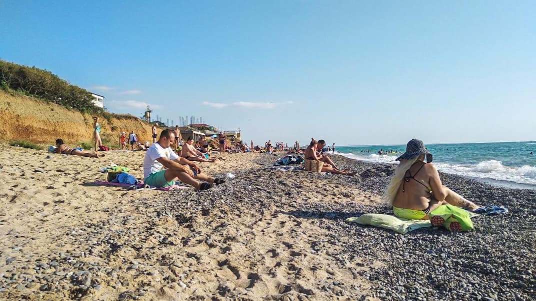 Люди сидят на берегу Черного моря в Николаевке в Крыму