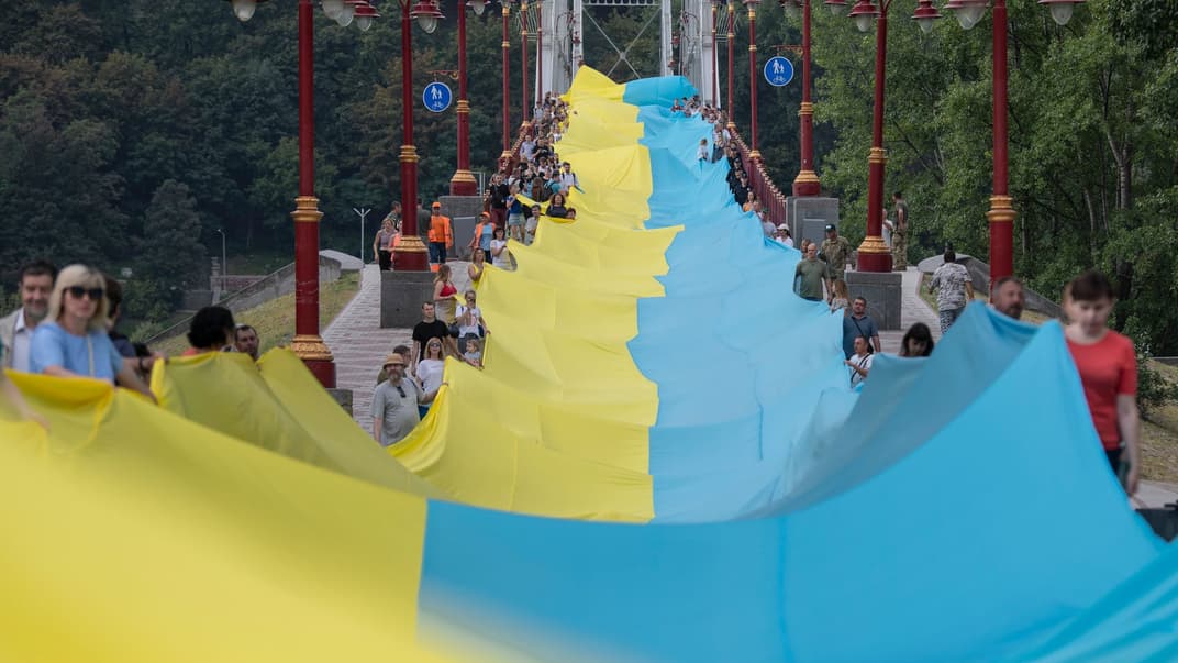 Активісти тримають гігантський український прапор під час акції «Україна єдина» у Києві 28 серпня. Акція символізує єдність українського народу в боротьбі за незалежність України. Прапор довжиною 430 метрів з'єднав обидва береги Дніпра