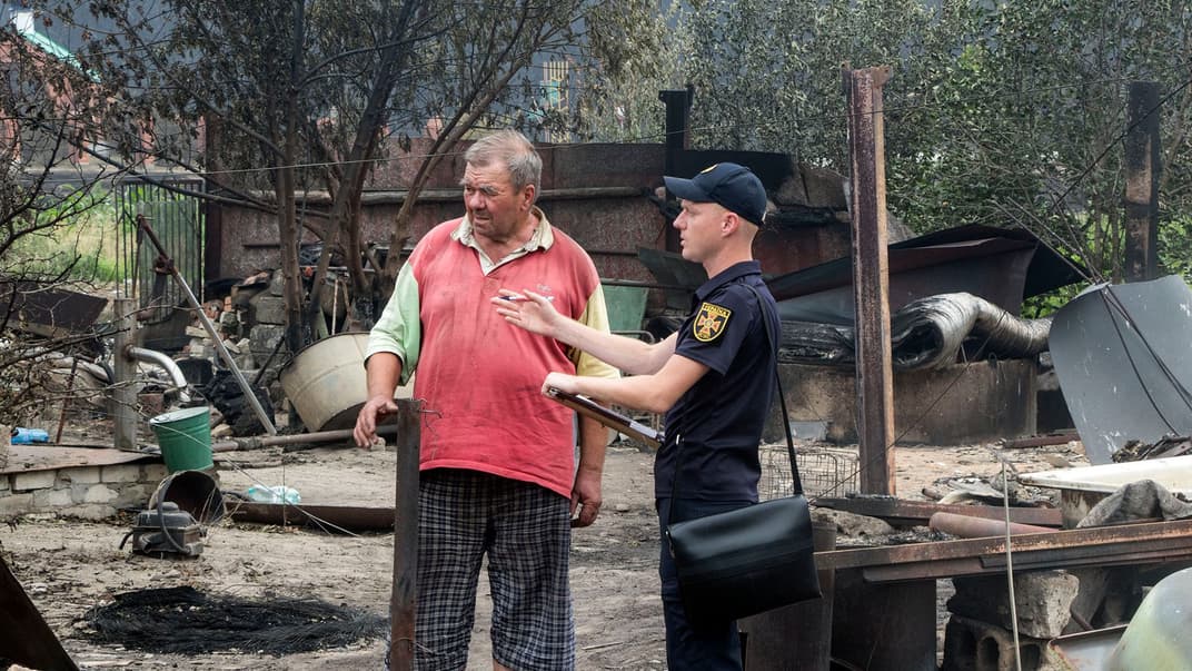 Постраждалий від пожежі місцевий житель села Смолянинове з рятувальником на Луганщині, 8 липня 2020 року