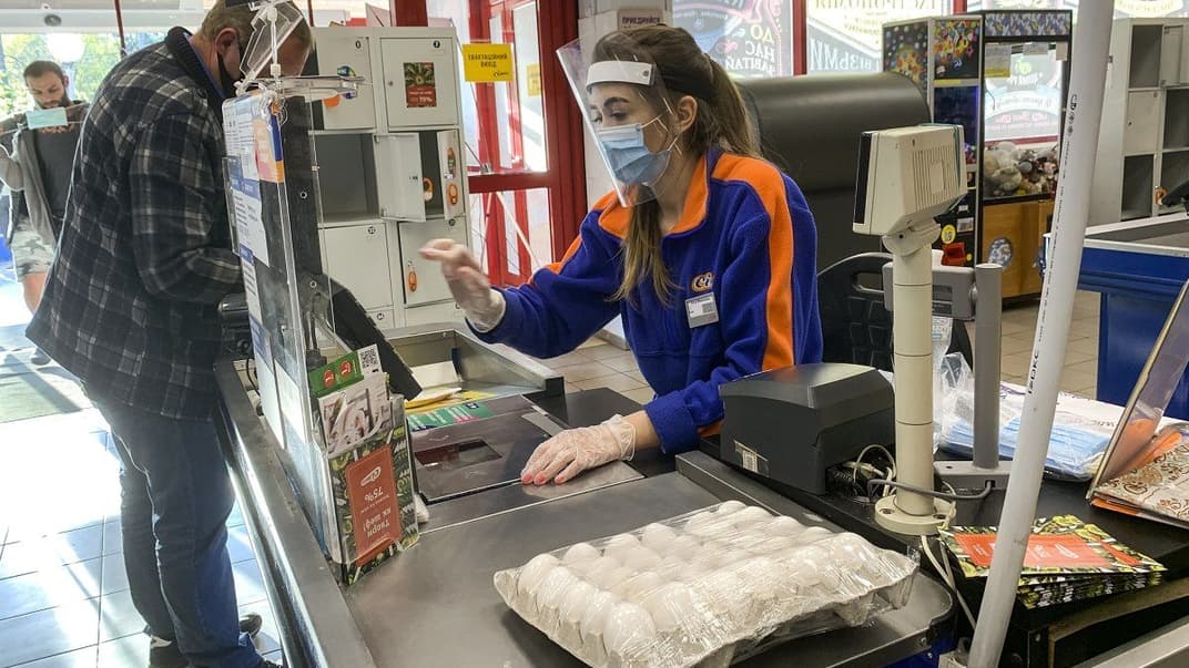 Касир у супермаркеті Києва працює в медичній масці, гумових рукавичках і з захисним екраном на обличчі під час карантину в Києві, 29 квітня 2020 року