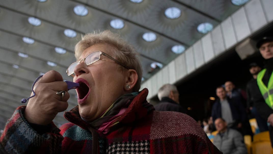 Женщина гудит в свисток во время дебатов между кандидатами на пост президента Украины Петром Порошенко и Владимиром Зеленским на стадионе «Олимпийский», Киев, 19 апреля 2019