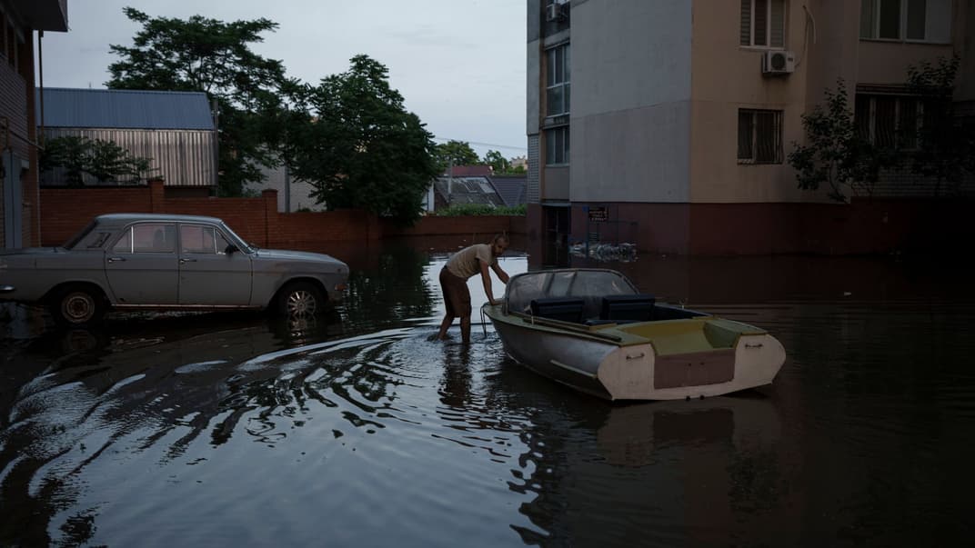 Чоловік штовхає човен у затопленому районі Херсона після підриву росіянами Каховської ГЕС, 7 червня 2023 року