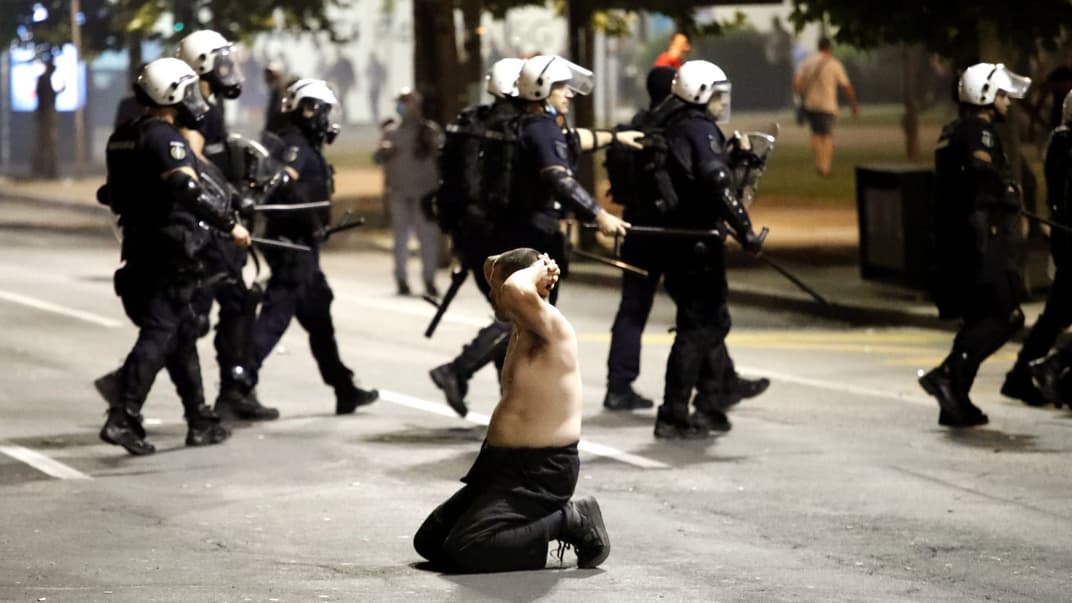 Чоловік стає на коліна перед правоохоронцями під час протестів біля будівлі сербського парламенту в Белграді, 7 липня 2020 року