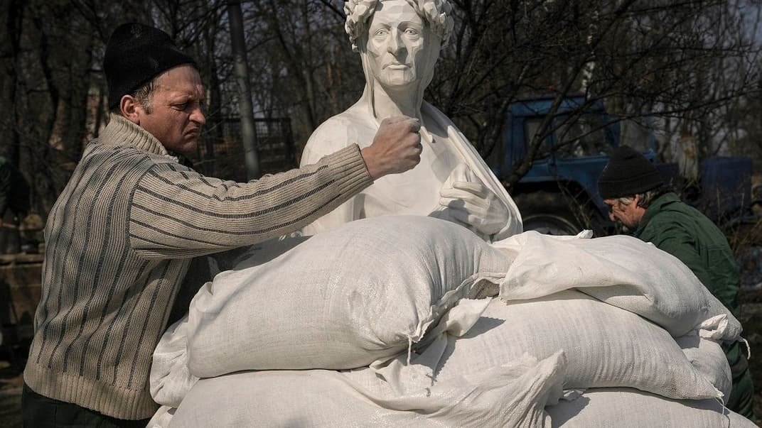 Комунальники накривають мішками з піском статую італійського поета та філософа Данте Аліг'єрі, щоб захистити її від можливих пошкоджень під час обстрілів, Київ, 23 березня 2022 року