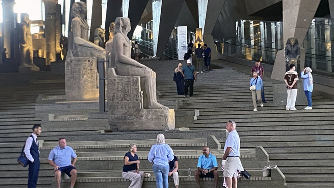 Відвідувачі проходять повз давньоєгипетські колосальні статуї вздовж парадних сходів у Великому Єгипетському музеї в Гізі, Єгипет, 15 жовтня 2024 року