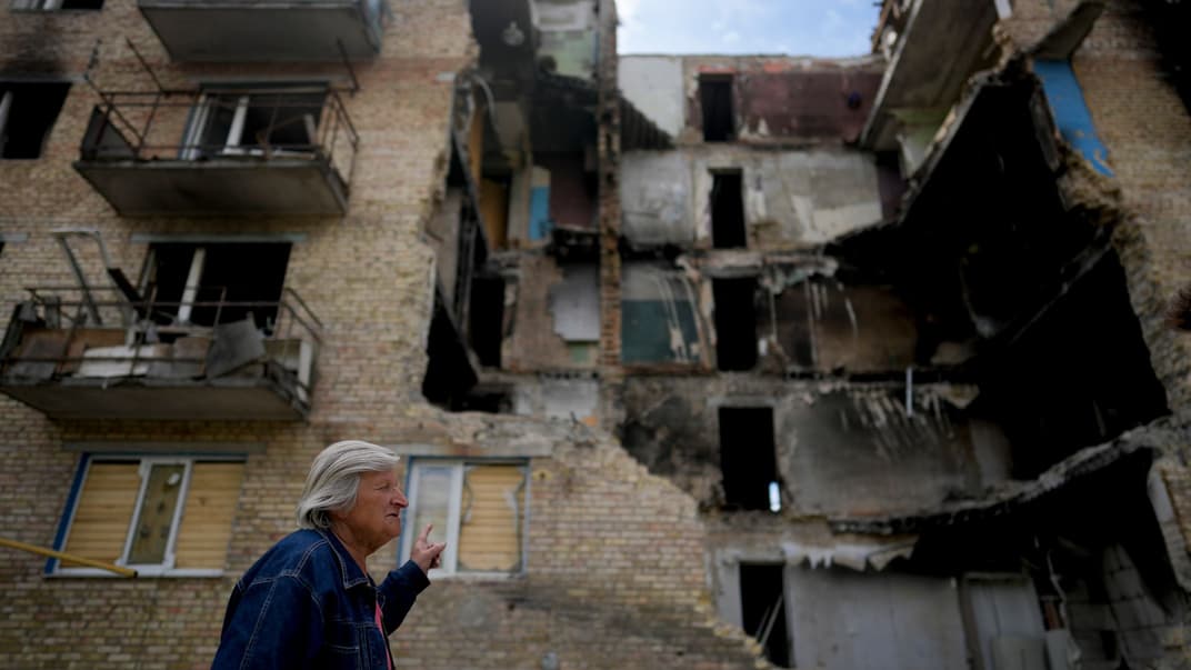 Жінка йде перед пошкодженим обстрілами будинку у селі Горенка, Київська область, 25 травня 2022 року