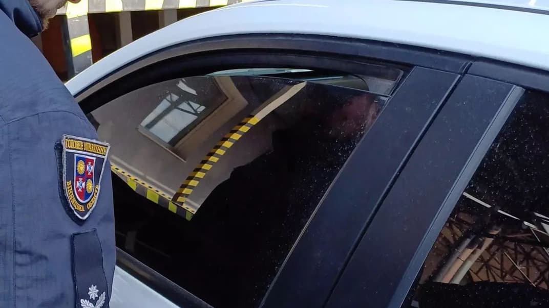 Поліціянт, якого викликали журналісти, стоїть біля авто, яке, ймовірно, стежило за медійниками