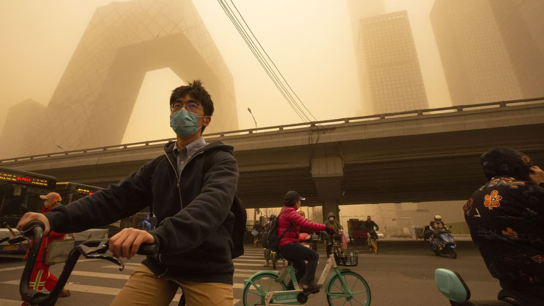 Люди на велосипедах во время песчаной бури в Пекине, 15 марта 2021 года