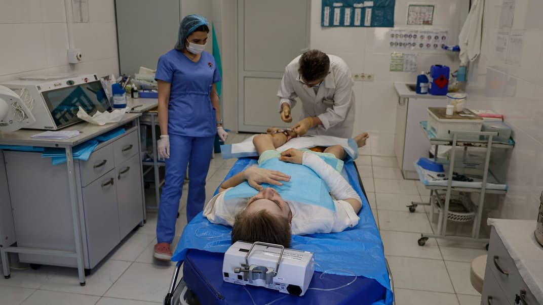 Врач лечит рану на ноге 20-летнего Никиты, украинского военнослужащего, в военном госпитале в Киеве, 5 мая 2023 года