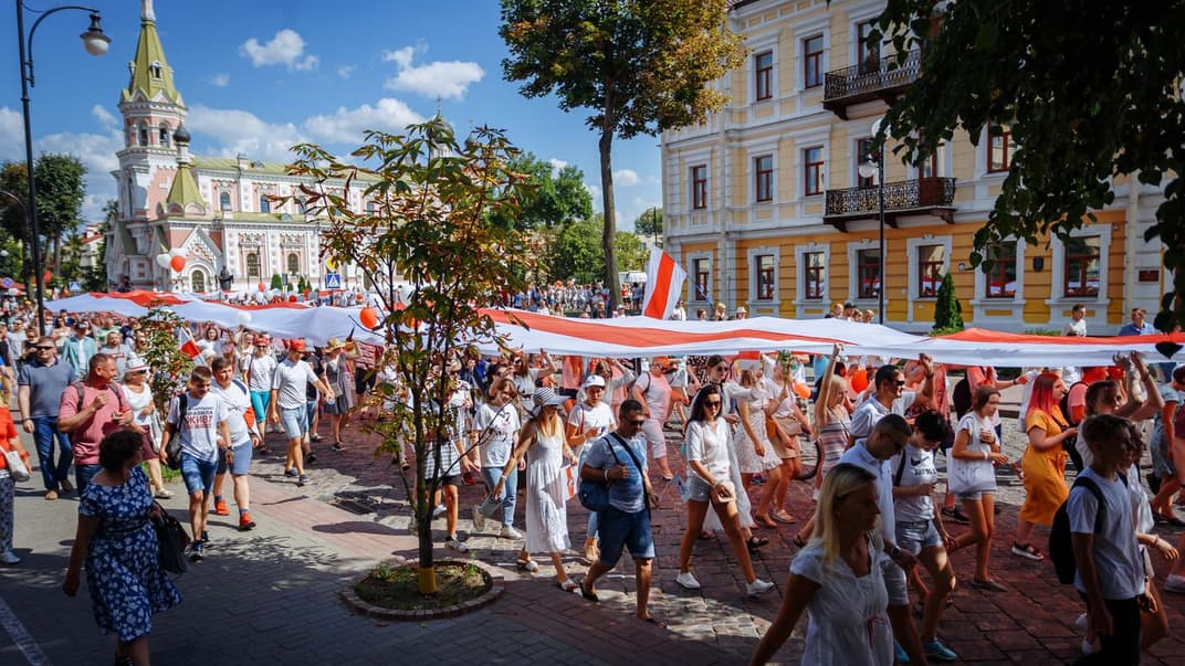 Білоруси несуть великий біло-червоно-білий прапор центральними вулицями Гродна