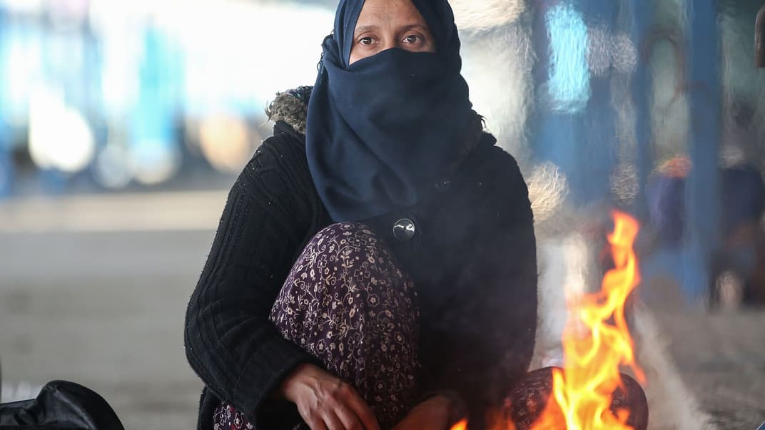 Сирийская беженка греется у костра на турецко-греческой границе вблизи города Эдирне, Турция, 5 марта 2020 года. Тысячи сирийских мигрантов пытаются попасть в Европу, убегая от гражданской войны, которая продолжается в их стране почти девять лет