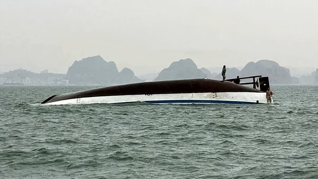 Чоловік стоїть на туристичному човні, який перекинувся в затоці Халонг у В’єтнамі