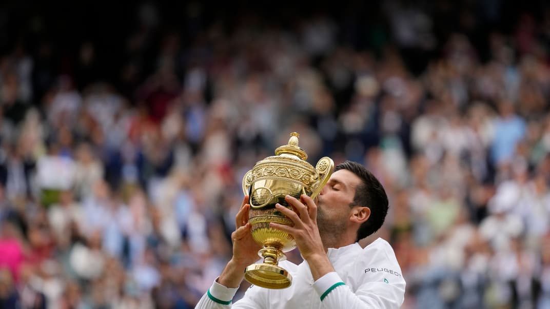 Сербский теннисист Новак Джокович целует кубок победителя Уимблдонского турнира, 11 июля 2021 года