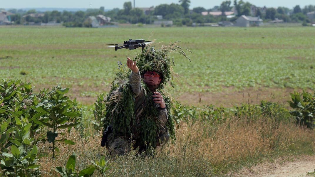 Оператор в маскировочной одежде принимает беспилотник после выполнения демонстрационного учебного полета на полигоне в Киеве, 15 июня 2023 года