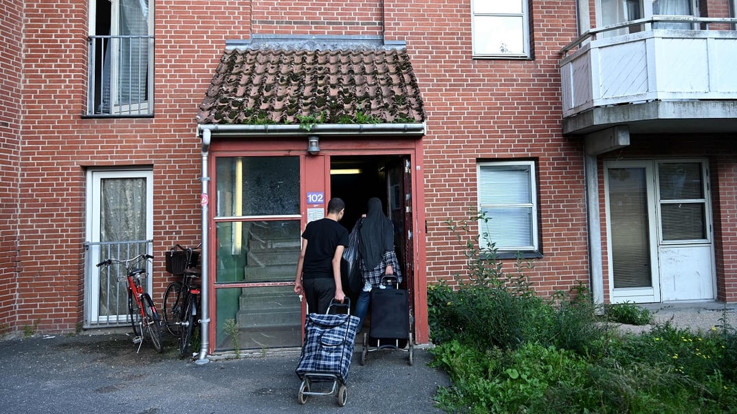 Мешканці житлового комплексу Мйолнерпаркен, де переважно проживають іммігранти, заходять у під’їзд, 28 серпня 2023 року