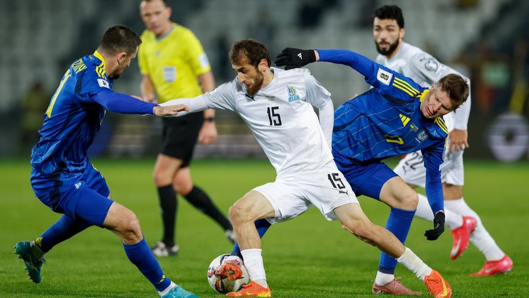 Українські футболісти Іван Калюжний та Артем Бондаренко борються за м’яч із півзахисником збірної Азербайджану Абдулахом Хайбулаєвим, 13 жовтня 2025 року