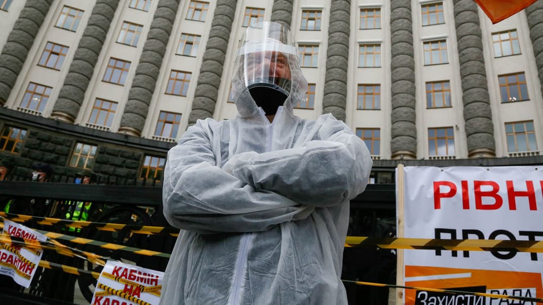 Працівник малого бізнесу в спеціальному костюмі для захисту від коронавірусу вимагає від уряду припинити карантин на акції протесту перед Кабміном у Києві