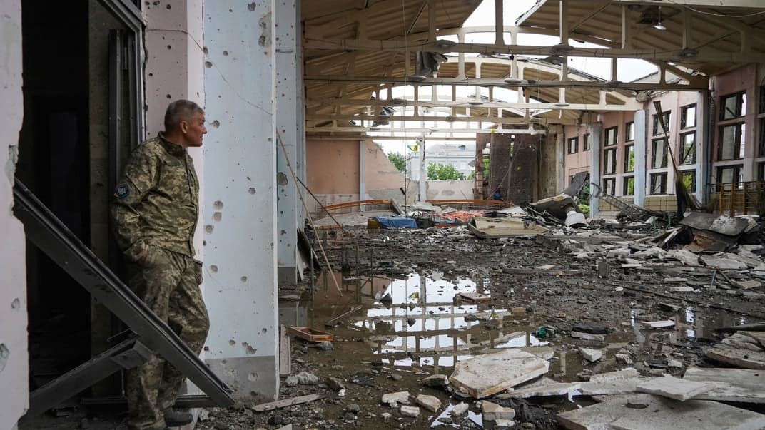 Український військовослужбовець дивиться на руїни спортивного комплексу Національного технічного університету в Харкові, пошкодженого під час обстрілу, 24 червня 2022 року