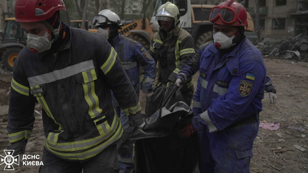 Спасатели несут погибшего человека на месте российского попадания, 24 апреля 2025 года