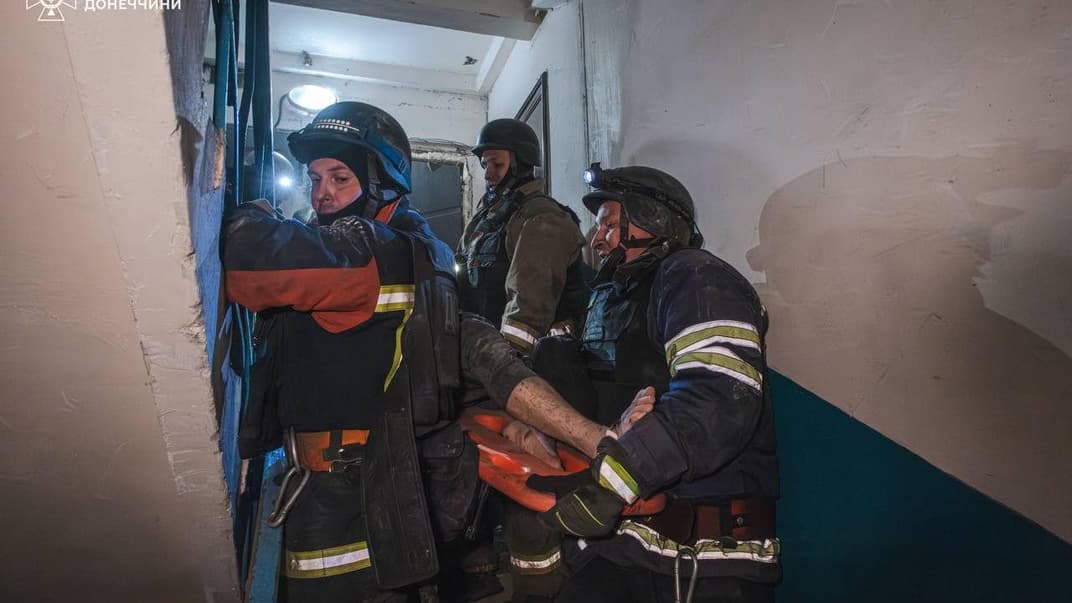 Рятувальники виносять пораненого внаслідок авіаудару по житловому будинку у Мирнограді