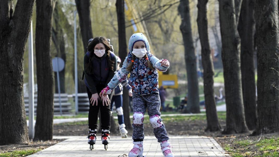 Жінка з донькою в медичних масках катаються на роликах в парку під час карантину в Києві, 28 березня 2020 року. Уряд озвучив попередні правила того, як після 22 травня працюватимуть дитячі садочки в Україні