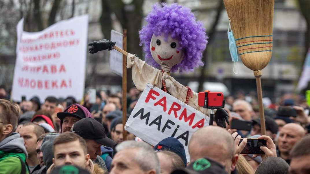 Протест антивакцинаторів у Києві, 3 листопада 2021 року. Жінка у центрі натовпу тримає опудало із надписом Farma Mafia, натякаючи на те, що пандемія коронавірусу і вакцинація може бути вигідна фармацевтам.