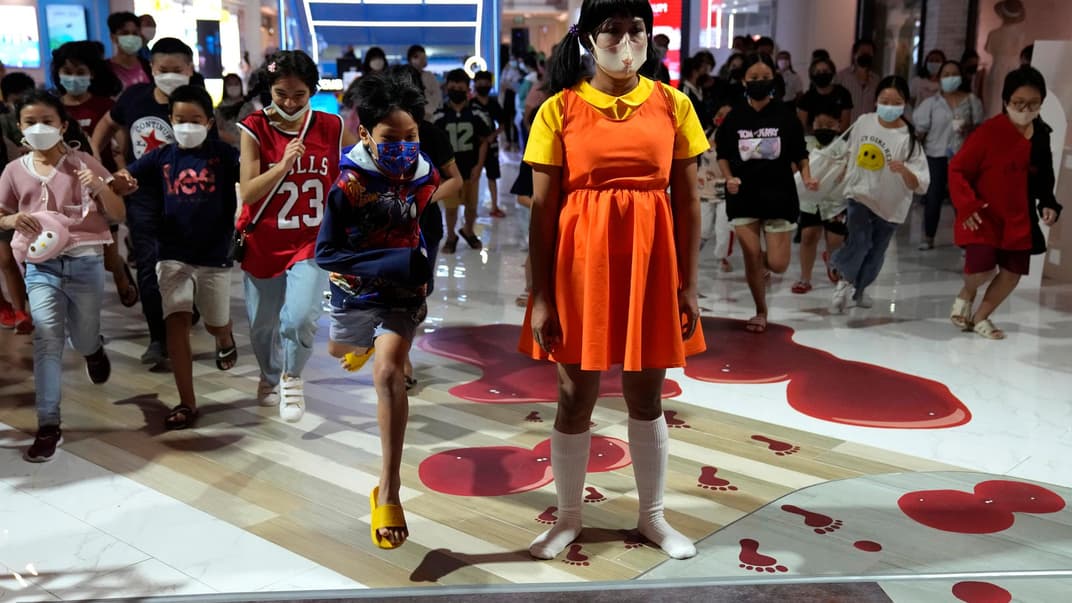 Жінка у костюмі з серіалу «Гра в кальмара» грає з дітьми в універмазі у Банкоку, Таїланд, 22 жовтня 2021 року