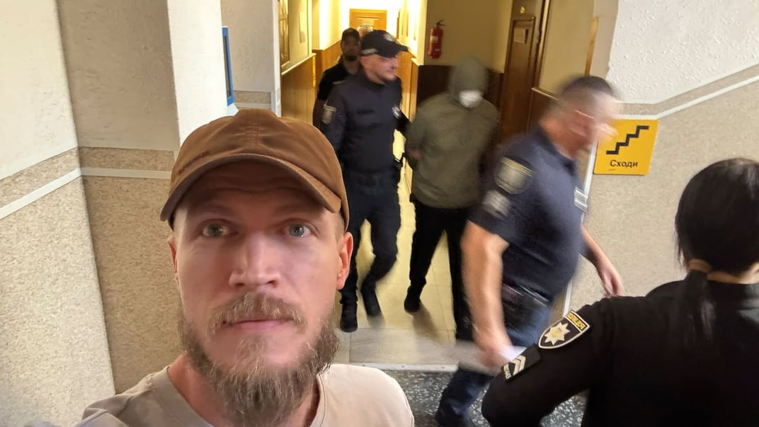 Олександр Ширшин на тлі того, як одного з підозрюваних виводять із зали суду, 11 вересня 2026 року Олександр Ширшин на тлі того, як одного з підозрюваних виводять із зали суду, 11 вересня 2026 року