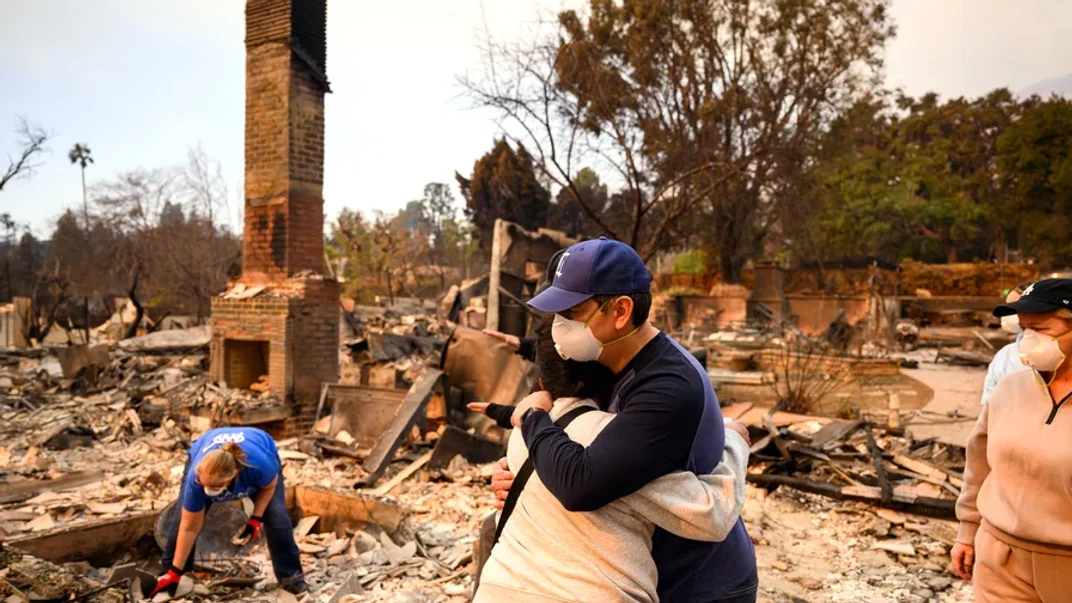 Члени сім’ї обіймаються, дивлячись на свій згорілий будинок під час пожежі в районі Альтадена в окрузі Лос-Анджелес, штат Каліфорнія, 9 січня 2025 року