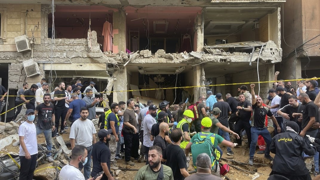 Люди собираются у поврежденного здания на месте израильского ракетного удара в южном пригороде Бейрута, 20 сентября 2024 года