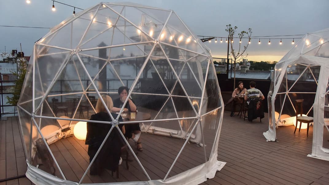 Відвідувачі вечеряють в спеціальних відокремлених кабінах в кафе на даху у Львові, 11 травня 2020 року. Серед перших кроків до послаблення карантину в Україні і дозвіл ресторанам і кафе приймати гостей на літніх терасах