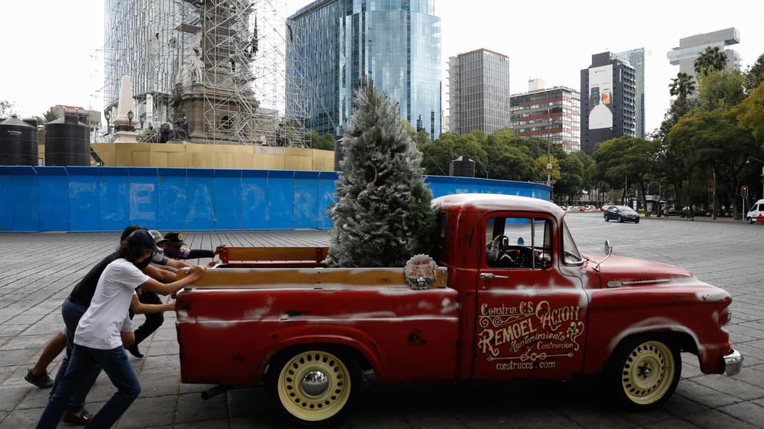 Чоловіки в захисних масках штовхають розбитий пікап, що перевозив ялинку, біля пам'ятника Ангелу Незалежності в Мехіко, 6 грудня 2020 року