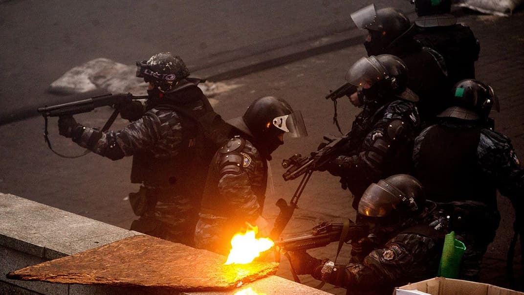 Бойцы полицейского спецподразделения «Беркут» стреляют в сторону протестующих на улице Грушевского в Киеве, 20 февраля 2014 года