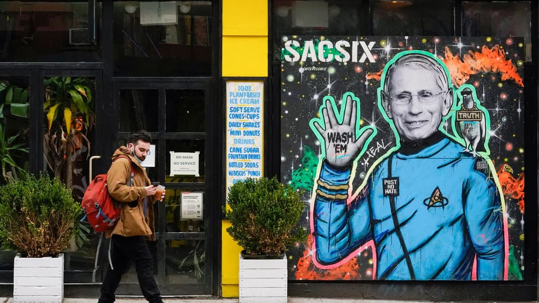 Пішохід у масці на підборідді йде повз зображення вуличного мистецтва, Нью-Йорк, 26 березня 2021 року
