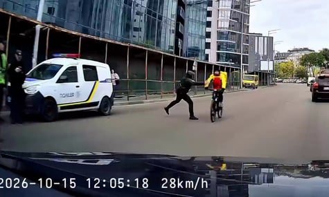 Кадр з відео, на якому поліціянт штовхає велосипедиста жезлом