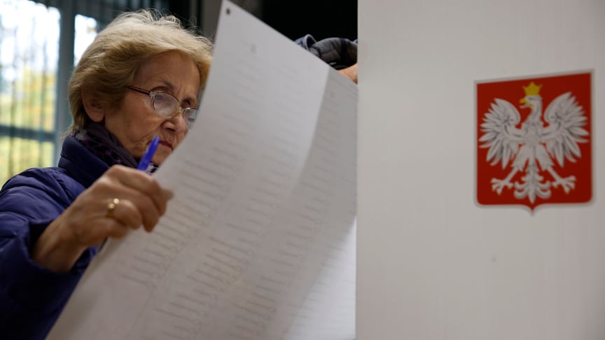 Женщина смотрит на бюллетени во время парламентских выборов в Варшаве, Польша, воскресенье, 15 октября 2023 года