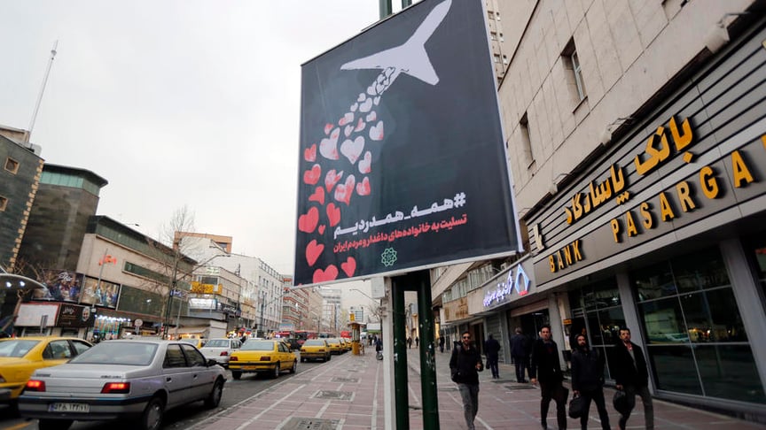 People walk past a poster reading in Persian 'we are all in pain and sympathize' to honor the victims of the January 8 Ukrainian passenger jet downing, in a street of Tehran, Iran on January 13, 2020.