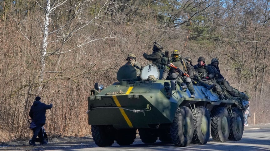 Чоловік з дитячим візком махає рукою українським захисникам на БТРі неподалік Києва, 10 березня 2022 року