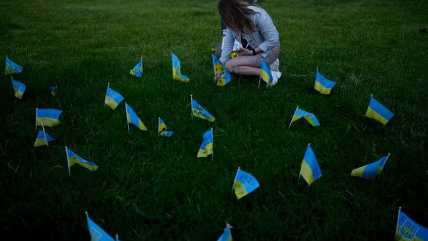 A woman leaves a flag in honor of those killed in the war with Russia, Kyiv, May 29, 2022