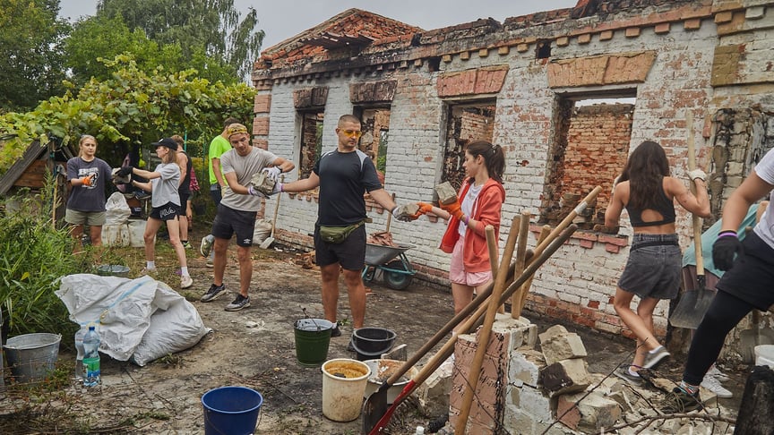 Волонтеры убираются во дворе разрушенного дома