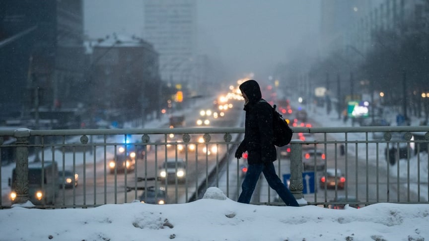 Ілюстративне фото. Чоловік іде по засніженому мосту над дорогою у Києві, лютий 2021 рік